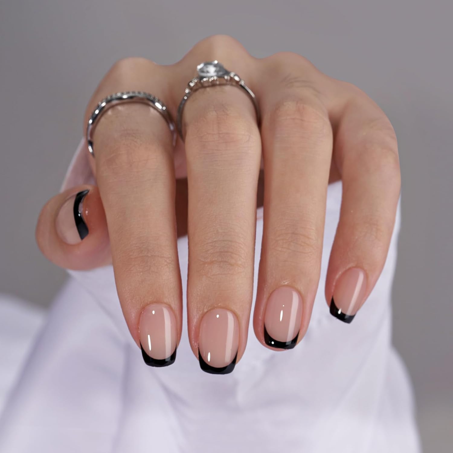 Hand wearing black French tip press-on nails short square shape